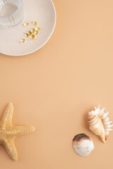 Top view of different shells and starfish with glass of water on beige background with negative space for text or space for product. Concept of taking vitamins