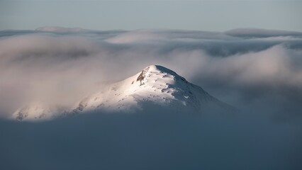 Sunlit mountain peak piercing a thick cloud blanket in early morning light