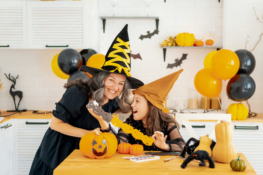 Halloween, a child with a mother in a witch costume is preparing for the Halloween holiday by coloring and carving tuquas and decorating the house for the holiday, happy Halloween