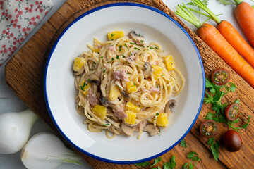 Spaghetti with pineapple, ham and cream sauce. Top view table with  decoration.