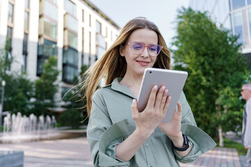 Fototapeta premium Young Woman Using a Tablet Outdoors in a Modern Urban Setting During Daytime
