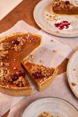 Fototapeta premium top view of a wooden table top with pumpkin pie and ceramic plates with pieces of pie on them