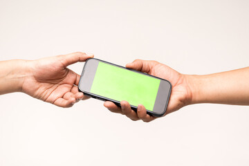 Closeup of men's hands holding cell telephone and green screen with blank copy space for your advertising text message or promotional conten.Hand sendng mobile on desk at office.