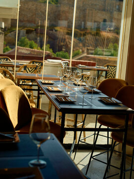 Elegant dining setup with empty wine glasses on table in a restaurant with a view of the city through the window.