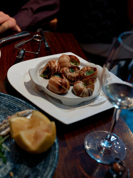 A plate of escargot served on a table at a fine dining restaurant with diners in the background.