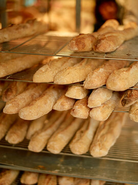 Freshly baked baguettes on a bakery display rack with a warm, soft-focus background.