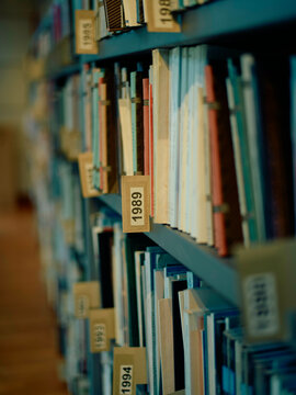 Shallow depth of field image showcasing numbered library bookshelves filled with a variety of books.