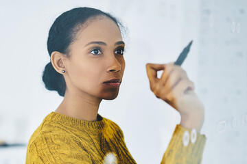 Concentrated african business woman writing information on modern board during working process in conference room, serious female entrepreneur planning startup project, concept of finance and trade