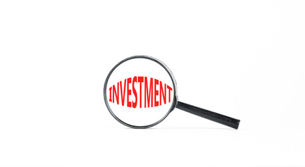 Investment symbol. Concept word Investment in beautiful magnifying glass. Beautiful white paper background. Business investment concept. Copy space.