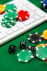 Chips and playing cards on a green felt surface near a computer keyboard during an online gaming session at home