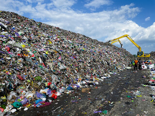 Heavy excavator vehicles work amidst piles of rubbish at landfills, towering mountains of rubbish...