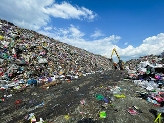 Heavy excavator vehicles work amidst piles of rubbish at landfills, towering mountains of rubbish filled with household waste. Photo concept for campaign purposes on the dangers of global warming