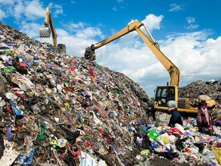 Heavy excavator vehicles work amidst piles of rubbish at landfills, towering mountains of rubbish...