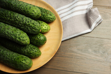 Fresh green cucumbers on wooden table, space for text