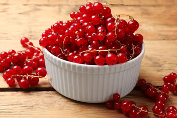 Fresh red currants in bowl on wooden table, closeup