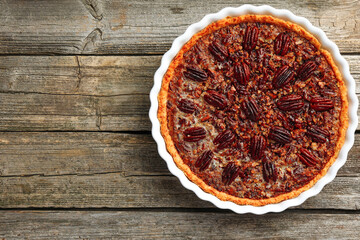 Delicious pecan pie in baking dish on wooden table, top view. Space for text