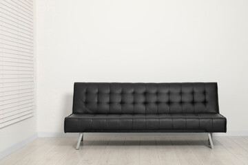 Comfortable couch near white wall. Interior design