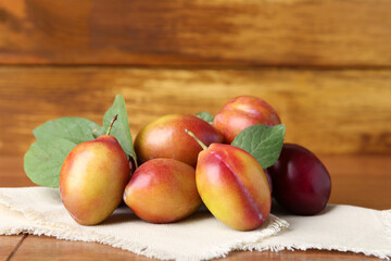 Ripe plums and leaves on wooden table, closeup