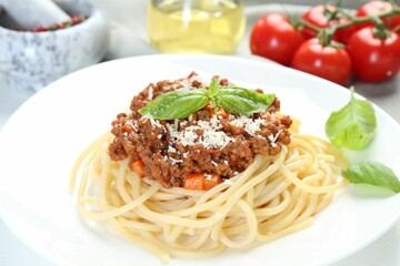 Delicious pasta bolognese with basil on table, closeup