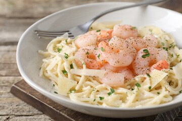 Delicious pasta with shrimps and cheese on wooden table, closeup