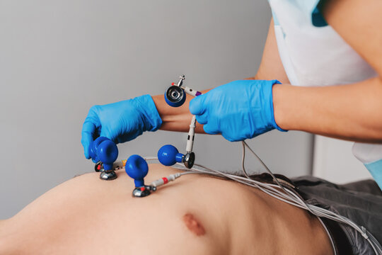 Cardiologist putting electrodes on chest of patient before making ecg