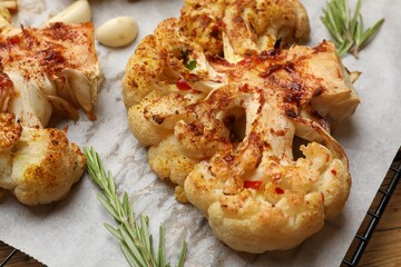 Tasty cauliflower steaks, rosemary and garlic on table, closeup