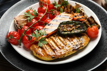 Delicious grilled vegetables and chicken breast on table, closeup