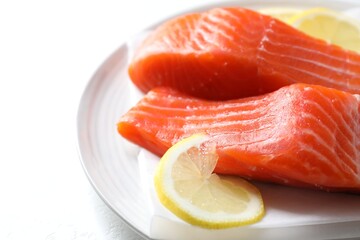 Pieces of fresh salmon with lemon on white table, closeup