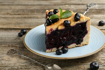Slice of homemade blueberry pie on wooden table, closeup