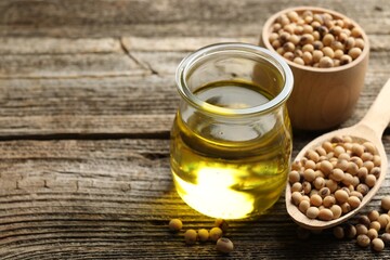 Cooking oil in jar and soybeans on wooden table, closeup. Space for text