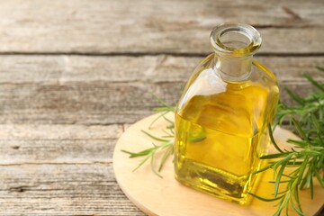 Cooking oil in bottle and rosemary on wooden table, closeup. Space for text