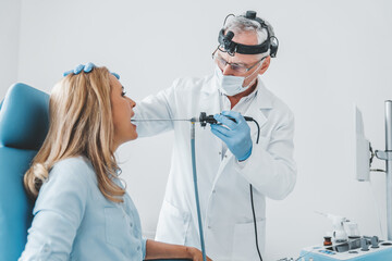 Doctor otolaryngologist making endoscopic examination of oral cavity for female patient at office