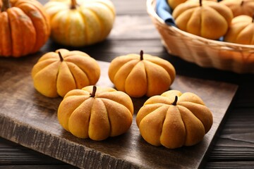 Tasty pumpkin shaped buns on wooden table, closeup