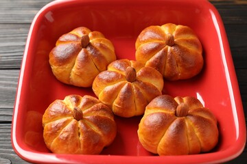 Baking tray with tasty pumpkin shaped buns on wooden table, closeup