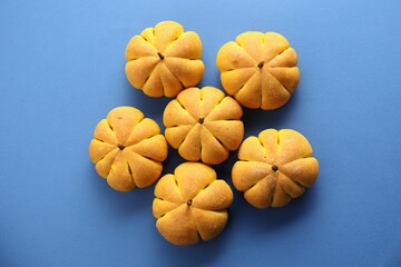 Pile of tasty pumpkin shaped buns on blue background, flat lay