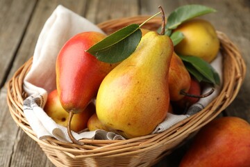 Ripe juicy pears in wicker basket on wooden table, closeup