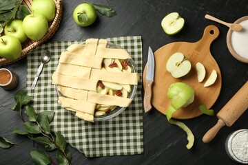 Flat lay composition with raw homemade apple pie and ingredients on dark textured table