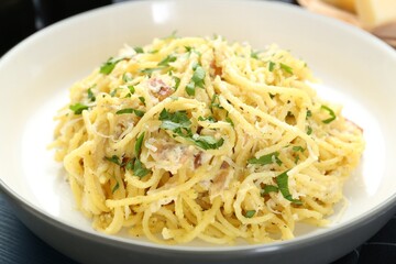 Delicious pasta Carbonara with ham and spices in bowl on table, closeup