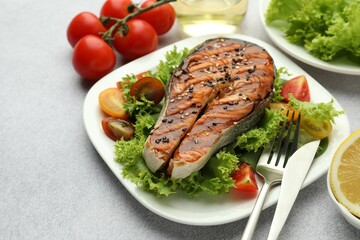 Tasty grilled salmon steak with vegetables served on light grey table, closeup