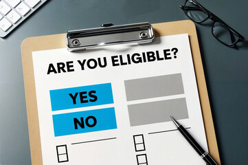A "yes" or "no" option selection for question "Are you eligible", on a clipboard, with a pen and a book in the background, suggesting the decision-making process.
