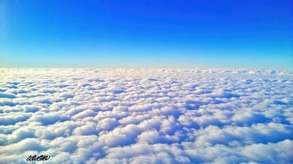 Obraz premium The world above the clouds: stunning clear blue sky with gentle fluffy formations, photographed from an aerial perspective.