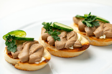 Savory canapes topped with creamy spread and cucumber slices served on toasted bread at a casual gathering