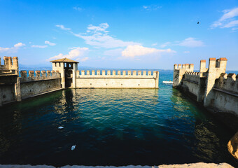 Medieval Fortress on Lake Garda, Sirmione, Italy
A scenic view of a medieval fortress with stone walls extending into the blue waters of Lake Garda in Sirmione, Italy.