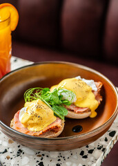 Poached eggs and ham toast with salad on top.