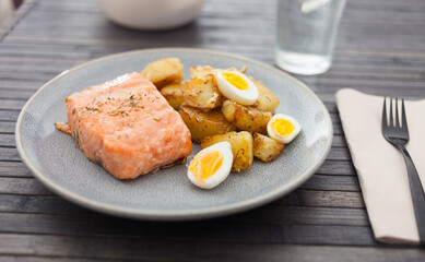 Baked salmon fillet with fried potato wedges and quail eggs halves
