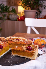 pumpkin pie on a wooden tray stands white on a table on the background of a white chair side view 