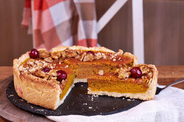 pumpkin pie on a wooden tray stands white on a table on the background of a white chair side view 
