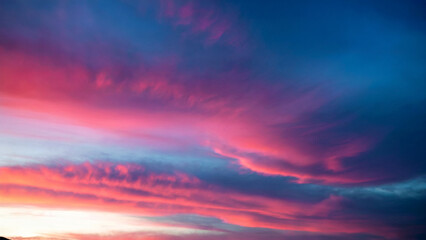 Obraz premium A breathtaking sky during what appears to be either dawn or dusk. The sky is painted with a vibrant palette of colors, ranging from deep blues to fiery oranges and pinks.