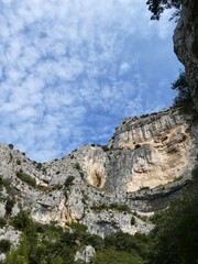 Looking up at the cliffs of the Rochers de Baude, Robion, France with mackerel cloud and blue sky