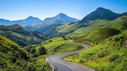Naklejka premium A winding road through lush green hills under a clear blue sky in the mountains during a sunny day